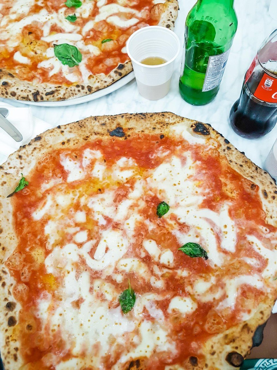 Two pizzas with bottled drinks in Naples, Italy